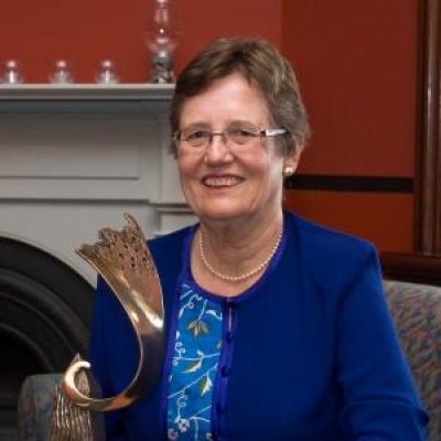 A woman in a blue dress holding a trophy